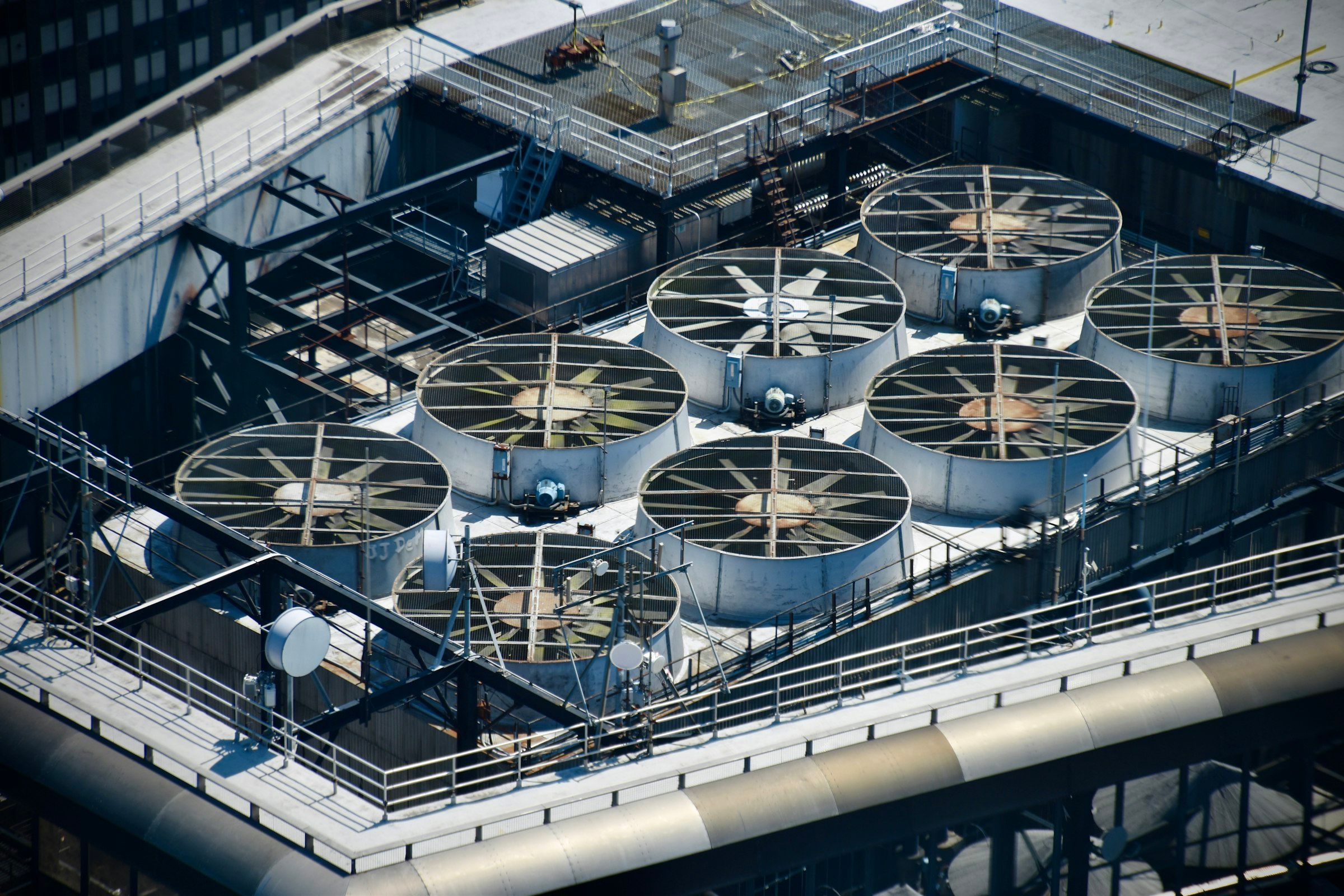 Acht grote ronde koelventilatoren in een dakopstelling, van bovenaf gezien.